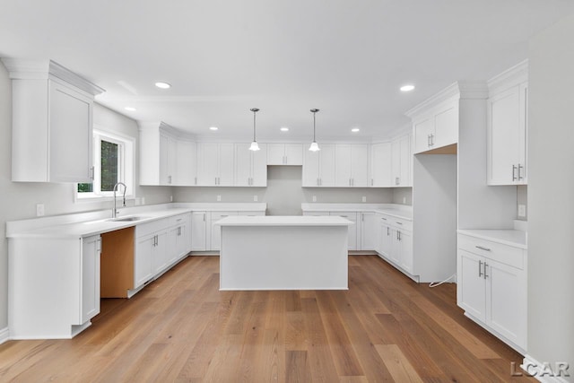 kitchen featuring pendant lighting, a kitchen island, white cabinetry, light hardwood / wood-style floors, and sink