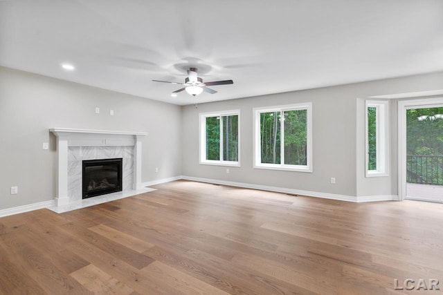 unfurnished living room featuring a premium fireplace, light hardwood / wood-style flooring, and ceiling fan