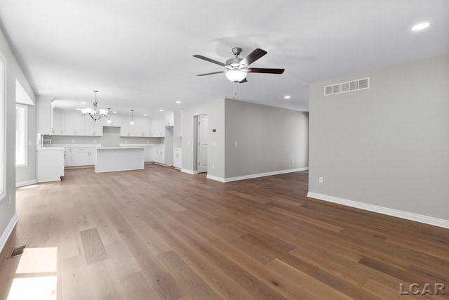 unfurnished living room featuring ceiling fan with notable chandelier and hardwood / wood-style floors