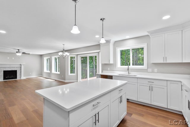 kitchen featuring white cabinetry, decorative light fixtures, sink, a high end fireplace, and a center island