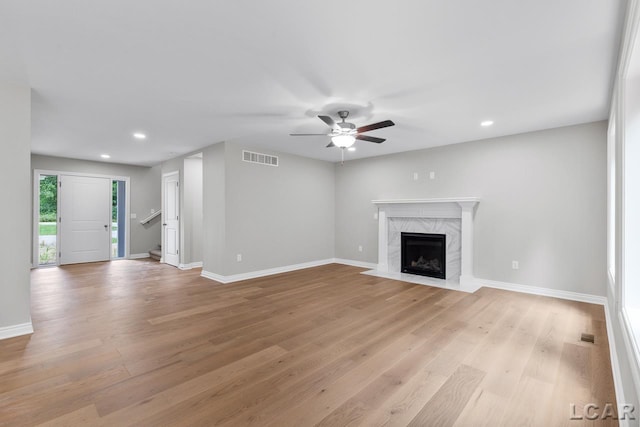 unfurnished living room featuring light hardwood / wood-style floors, ceiling fan, and a fireplace