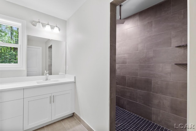 bathroom with tile patterned flooring, tiled shower, and vanity