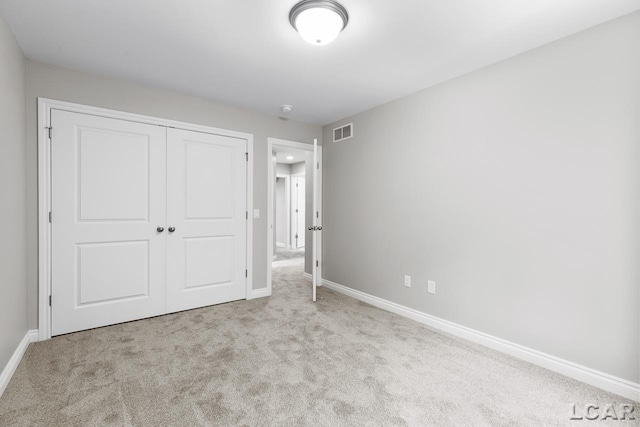 unfurnished bedroom featuring light colored carpet and a closet