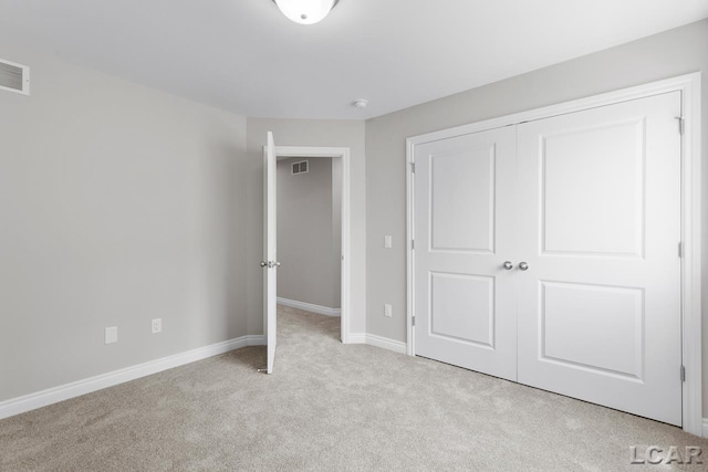 unfurnished bedroom with light colored carpet and a closet