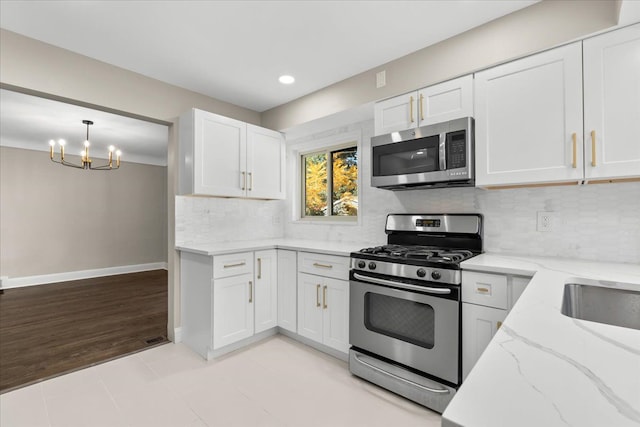 kitchen with white cabinets, decorative light fixtures, stainless steel appliances, and an inviting chandelier