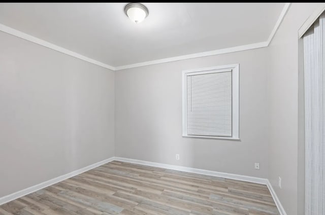 spare room featuring light wood-type flooring and ornamental molding