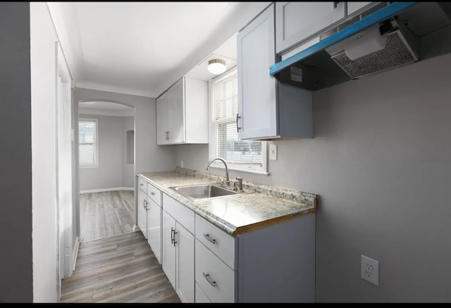 kitchen with white cabinetry, sink, plenty of natural light, and light wood-type flooring