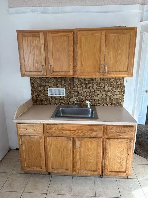 kitchen featuring backsplash, sink, and light tile patterned floors