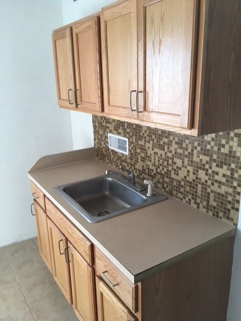 kitchen with backsplash, light brown cabinetry, and sink