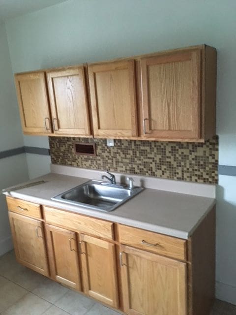 kitchen with decorative backsplash, light tile patterned floors, and sink