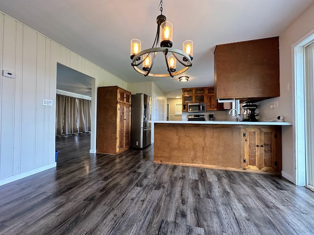 kitchen with kitchen peninsula, stainless steel appliances, dark wood-type flooring, pendant lighting, and an inviting chandelier