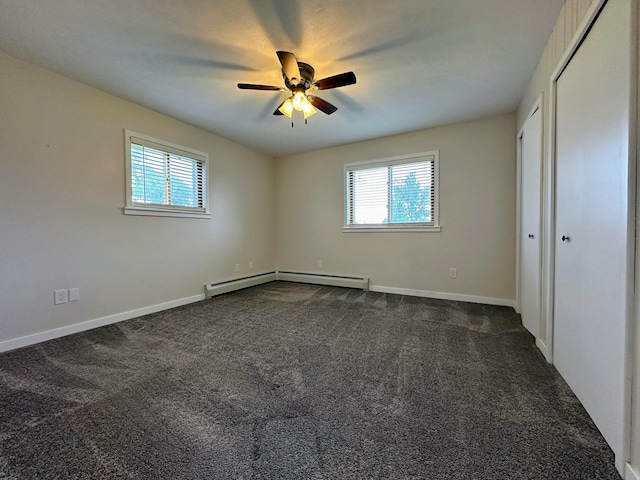 empty room with baseboard heating, ceiling fan, a healthy amount of sunlight, and dark carpet