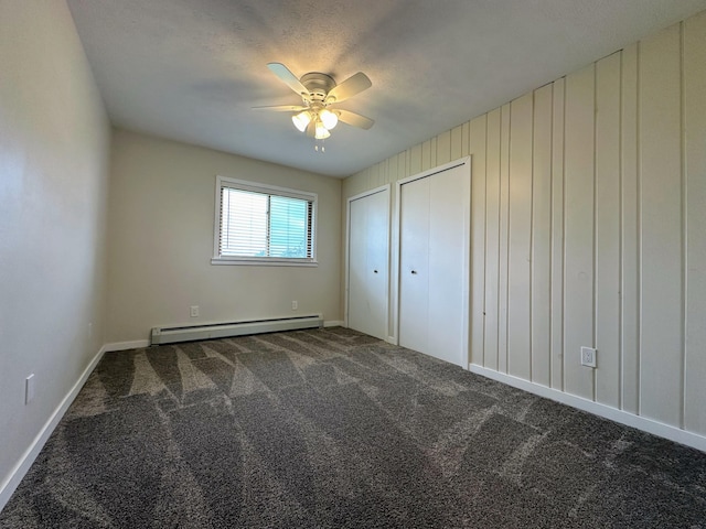 unfurnished bedroom with ceiling fan, a baseboard radiator, two closets, and dark carpet