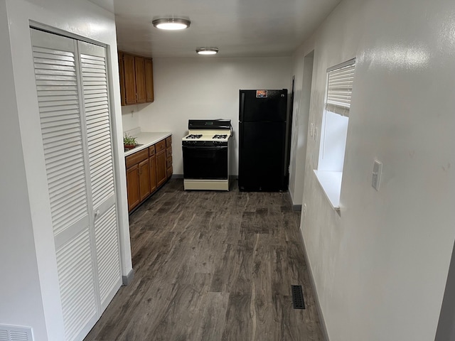 kitchen with black refrigerator, white range with gas stovetop, and dark wood-type flooring