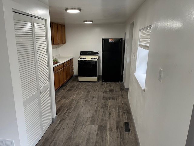 6801 Ravenswood Rd, Kimball, MI 48074 - kitchen featuring white range with gas stovetop, freestanding refrigerator, dark wood-style floors, brown cabinets, and light countertops
