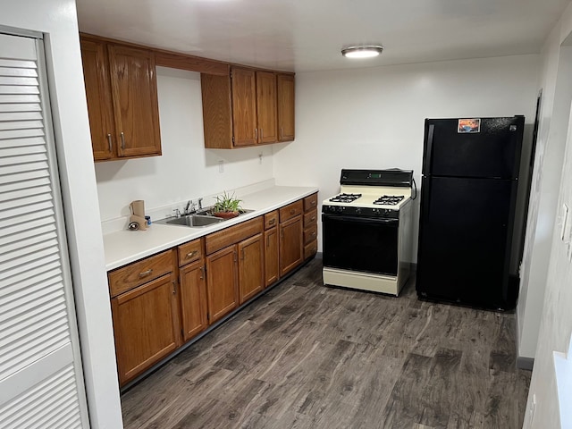 kitchen featuring sink, black refrigerator, dark wood-type flooring, and white gas range oven