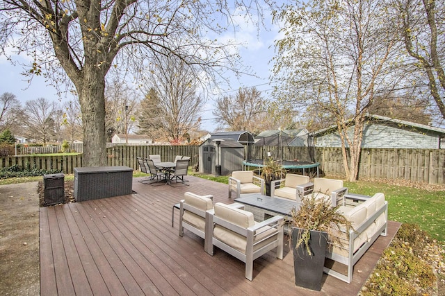 wooden terrace with an outdoor hangout area, a shed, and a trampoline