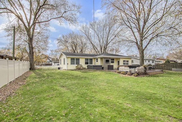 rear view of house featuring a yard and a hot tub