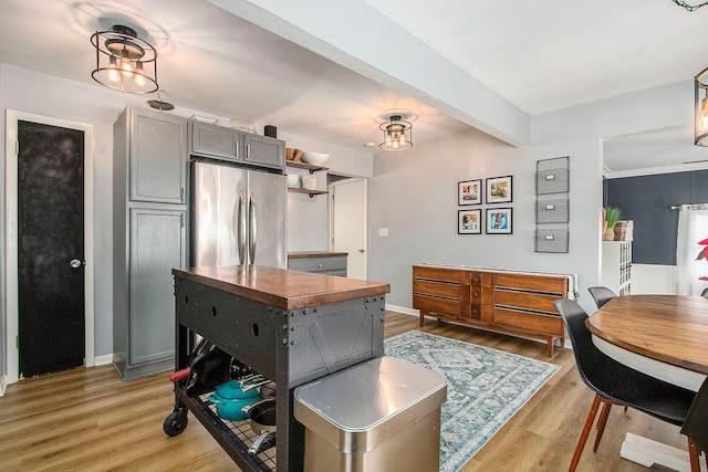 kitchen with gray cabinetry, stainless steel fridge, a chandelier, and light wood-type flooring