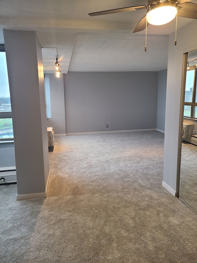 carpeted empty room with a textured ceiling and a baseboard heating unit