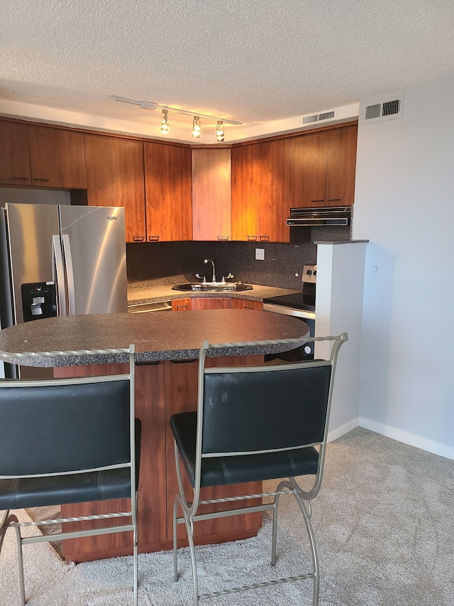 8900 E Jefferson Ave # 908 # 909, Detroit, MI 48214 - kitchen with stainless steel appliances, ventilation hood, a sink, a textured ceiling, and brown cabinets