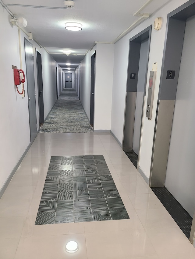 8900 E Jefferson Ave # 908 # 909, Detroit, MI 48214 - corridor with elevator, tile patterned flooring, and baseboards