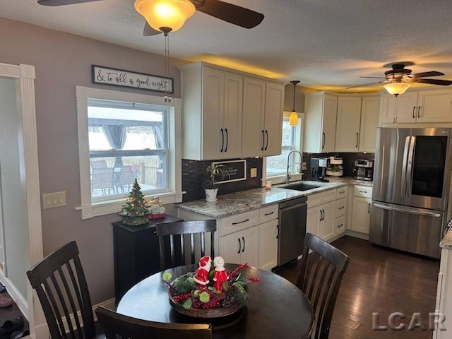 kitchen featuring decorative backsplash, light stone countertops, stainless steel appliances, sink, and pendant lighting