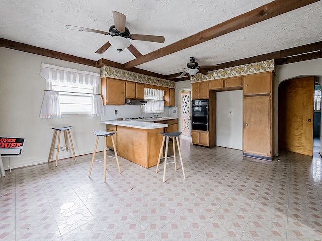 kitchen featuring a breakfast bar, white appliances, ceiling fan, a textured ceiling, and kitchen peninsula