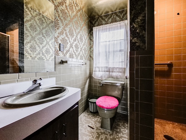 bathroom featuring tile patterned floors, vanity, toilet, and tile walls