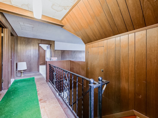 hallway with vaulted ceiling and wood walls