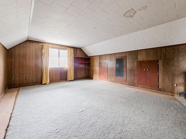 additional living space with carpet flooring, wooden walls, and lofted ceiling