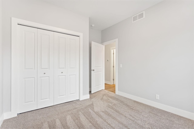 unfurnished bedroom with light colored carpet and a closet