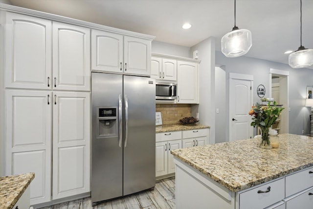 kitchen with backsplash, stainless steel appliances, a center island, white cabinetry, and hanging light fixtures