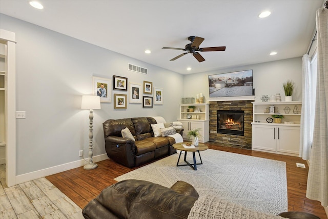 living room with ceiling fan, a fireplace, and light hardwood / wood-style flooring