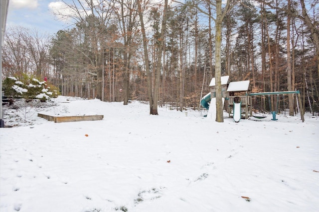 yard covered in snow featuring a playground