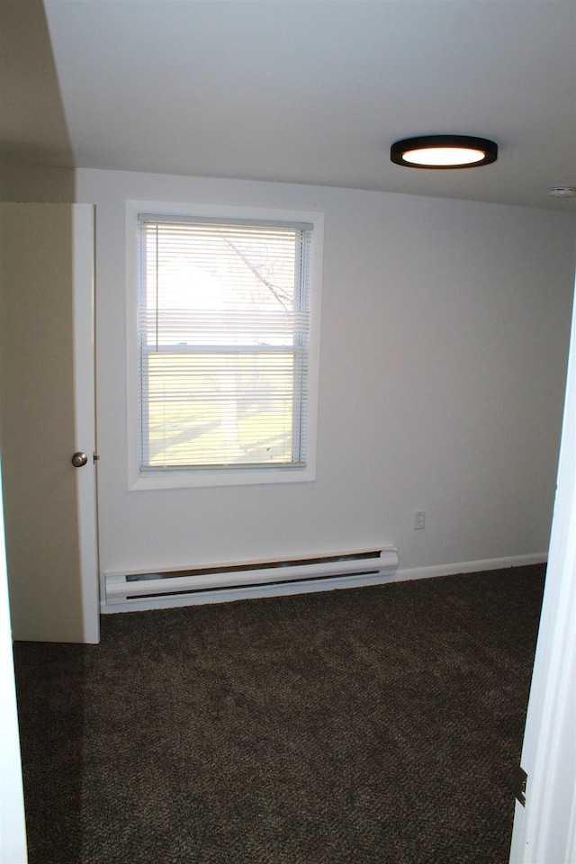 empty room with dark carpet and a baseboard radiator