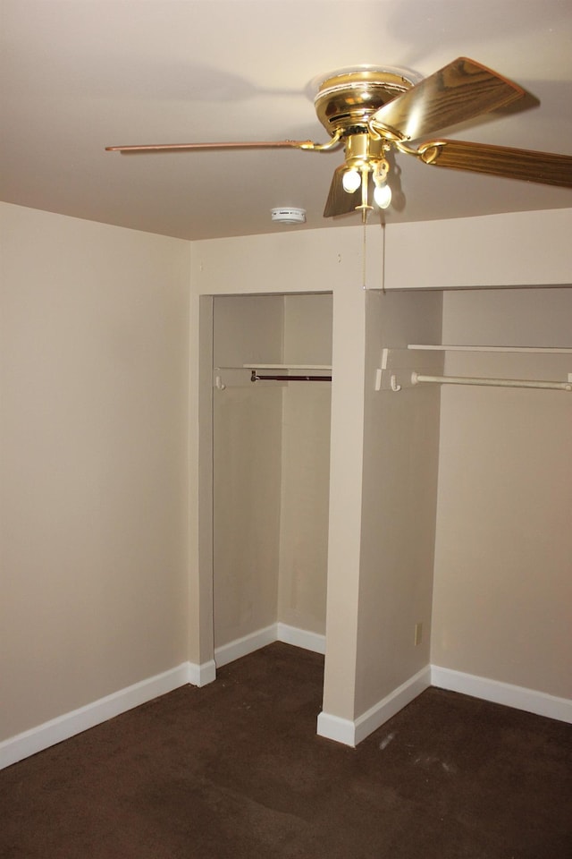 unfurnished bedroom with ceiling fan, dark carpet, and a closet