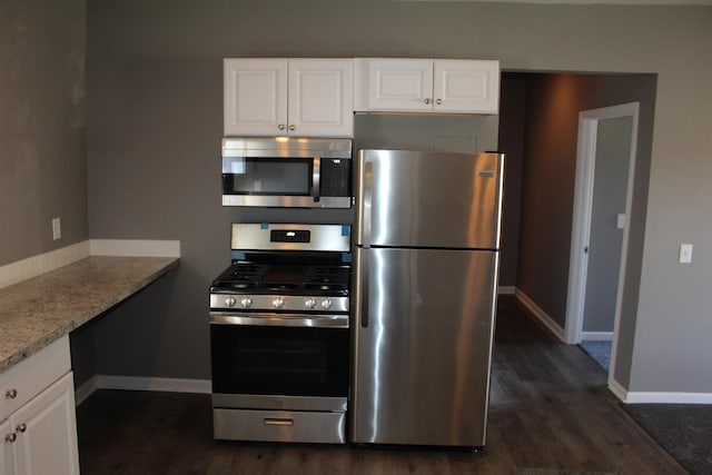 kitchen featuring white cabinetry, dark hardwood / wood-style flooring, stainless steel appliances, and light stone counters