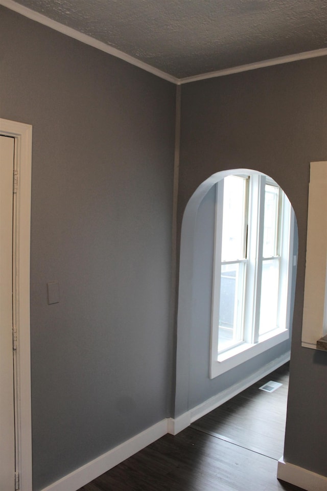 unfurnished room with ornamental molding, a textured ceiling, and dark wood-type flooring