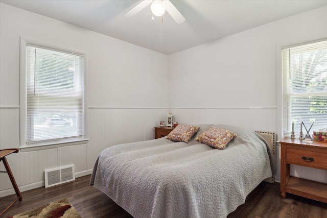 bedroom featuring ceiling fan, dark hardwood / wood-style flooring, and multiple windows