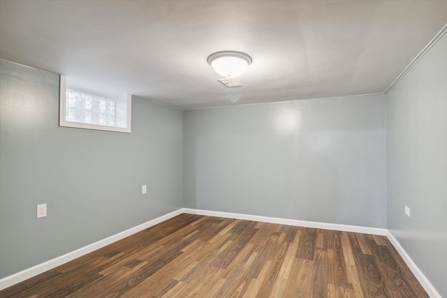 basement with crown molding and dark wood-type flooring