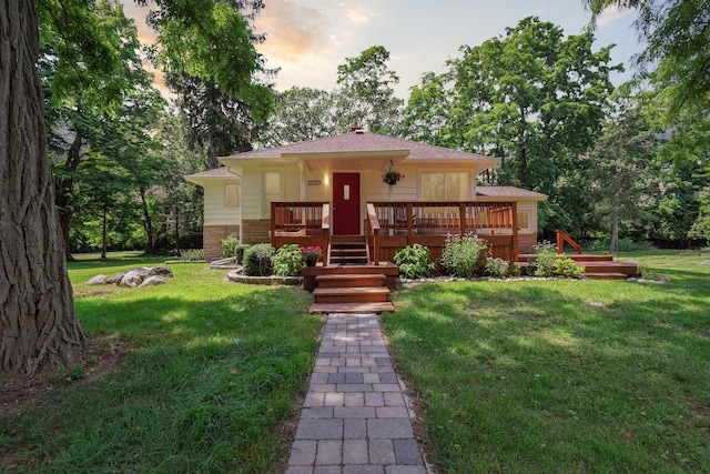 view of front facade with a wooden deck and a lawn