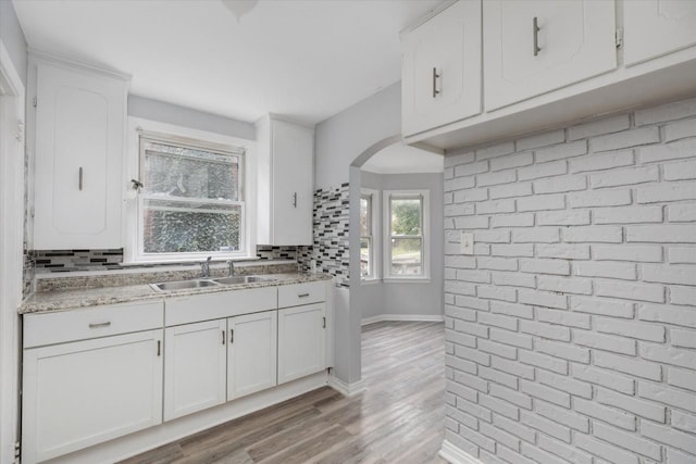 kitchen featuring white cabinets, backsplash, light hardwood / wood-style floors, and sink