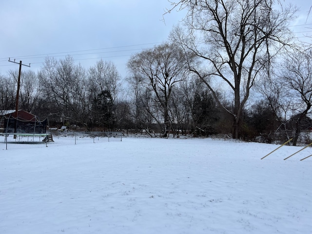 yard layered in snow with a trampoline