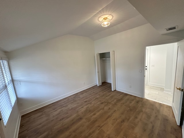 unfurnished bedroom featuring lofted ceiling, dark hardwood / wood-style flooring, and a closet