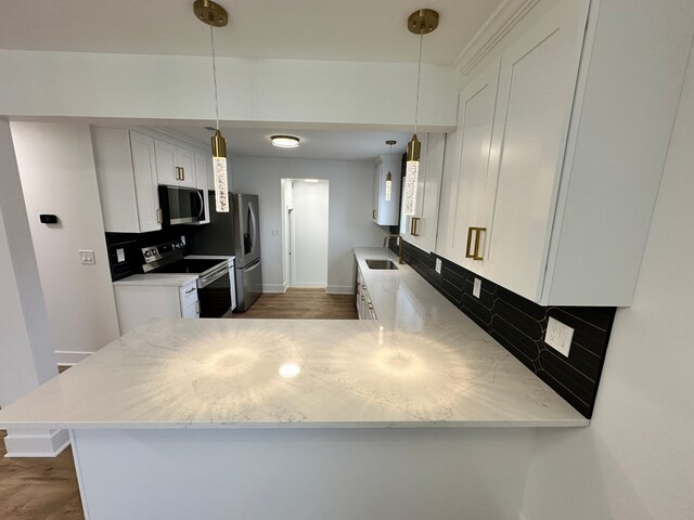 kitchen with white cabinets, stainless steel appliances, kitchen peninsula, and decorative backsplash