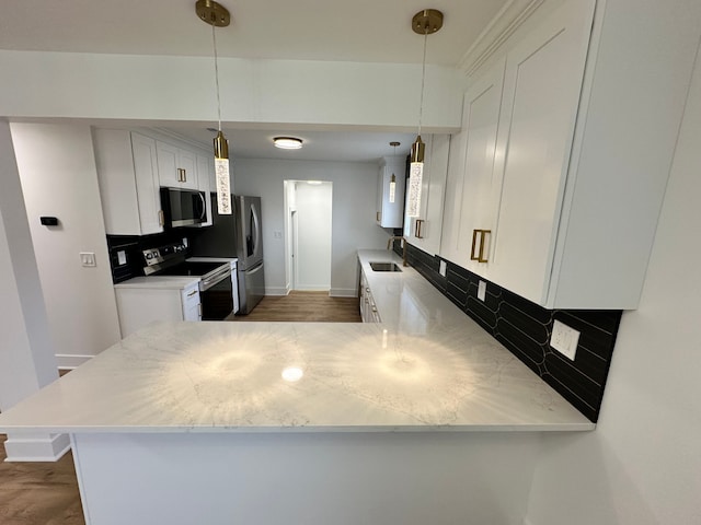 kitchen with appliances with stainless steel finishes, kitchen peninsula, and white cabinets