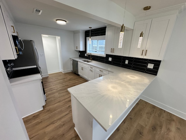 kitchen featuring sink, dishwasher, white cabinetry, hanging light fixtures, and kitchen peninsula