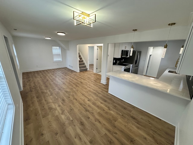 kitchen with white cabinetry, stainless steel fridge, hardwood / wood-style floors, and electric range oven