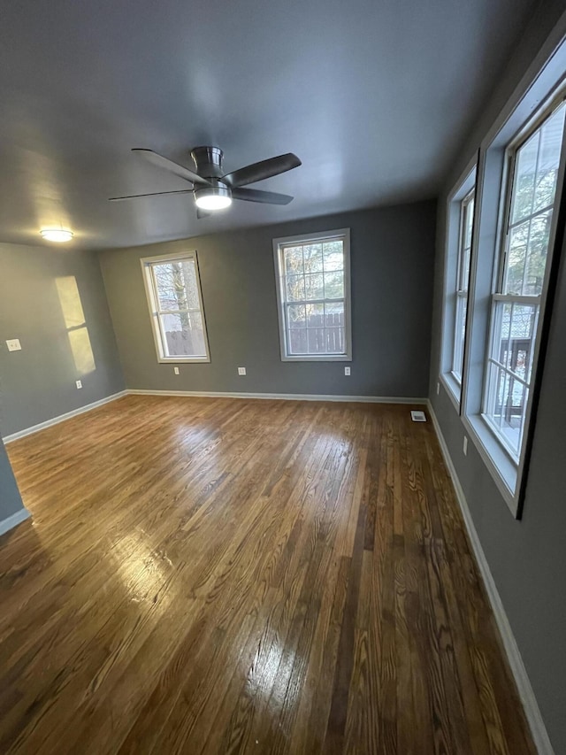 spare room with ceiling fan, plenty of natural light, and dark hardwood / wood-style floors